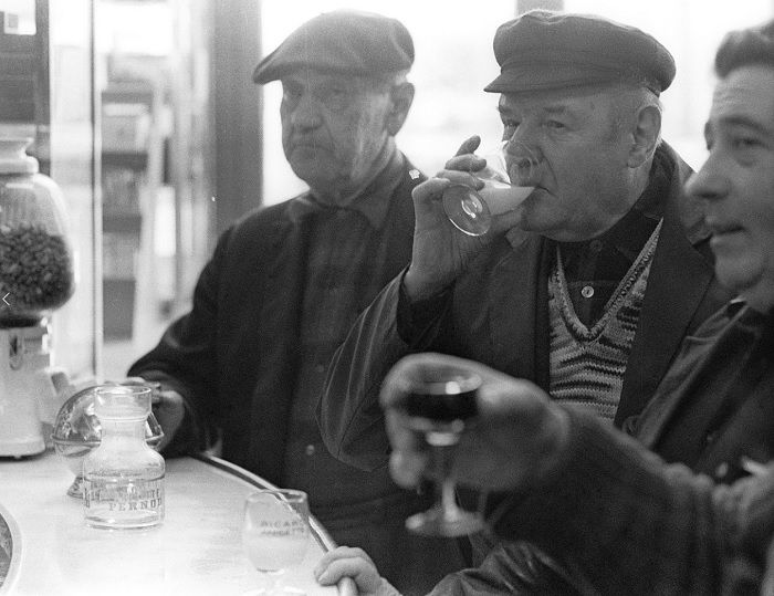 Three old fellas in flat caps sipping drinks in a cafe