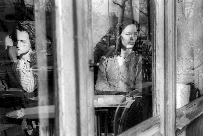 Man and woman sitting separately seen through a window