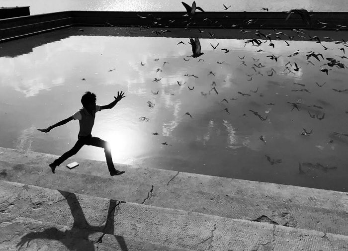 Child running next to a concrete pond