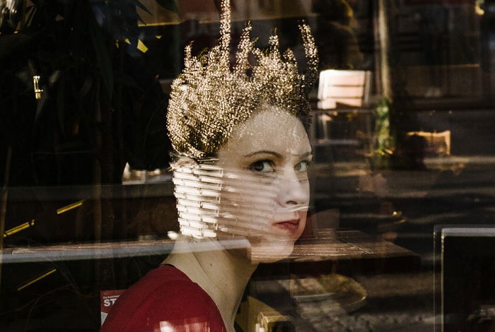 Woman looking through the reflection of a window