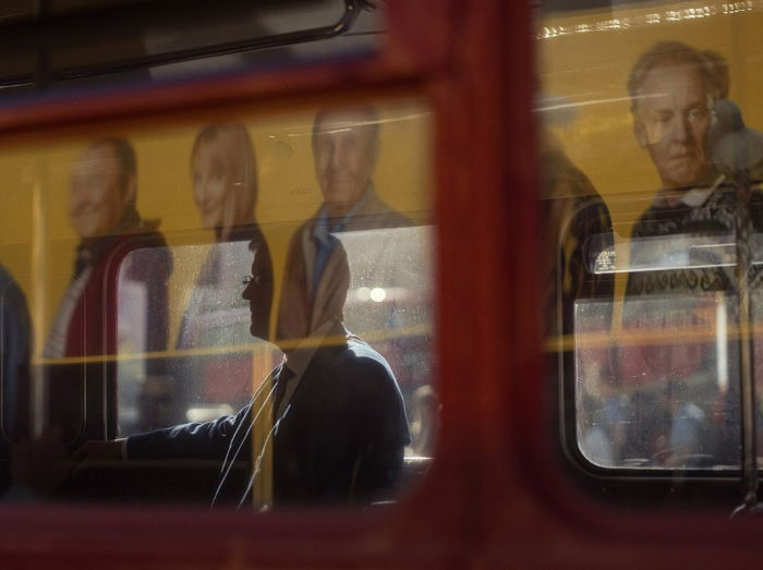 Man seen through bus window with reflections on glass