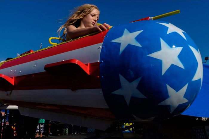 Young girl sitting in a USA rocket ride