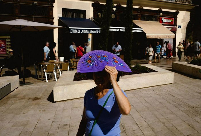 Woman protecting herself from the sun with a purple fan