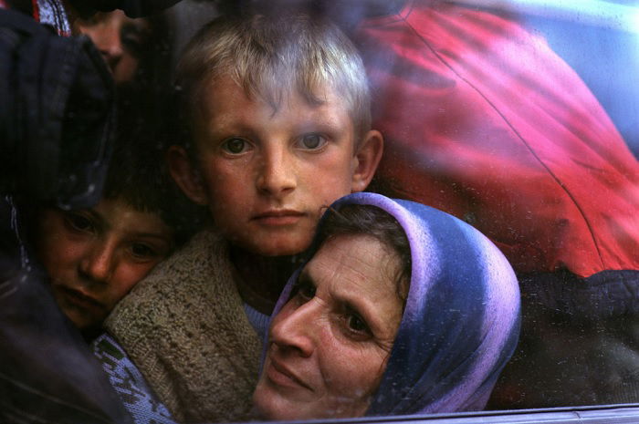 Boy, woman, and others squeezed into a vehicle