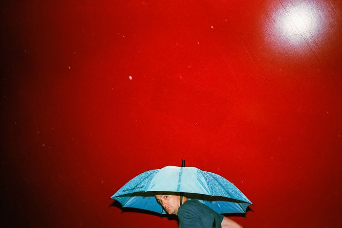 Man with umbrella against a red wall