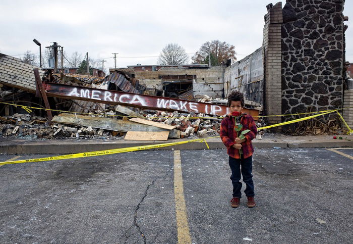 Young boy in front of a collapsed building