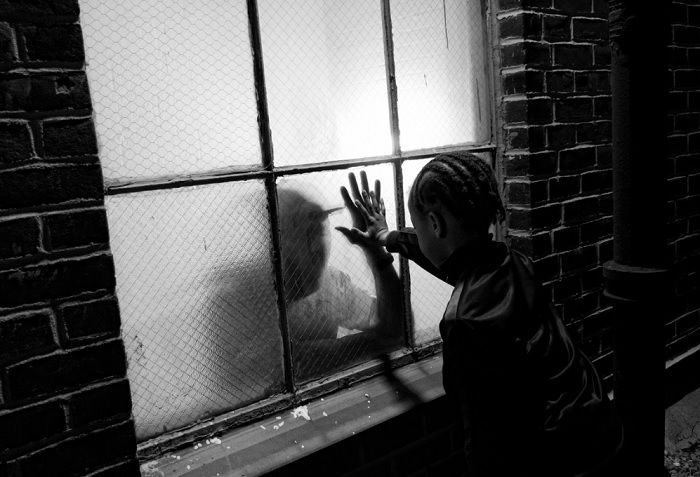 Boy touching hands with a man on the other side of a frosted window