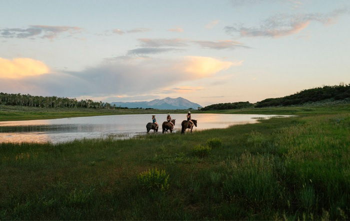 Three horse riders by lake