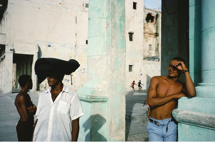 Topless man leaning against wall in Havana street