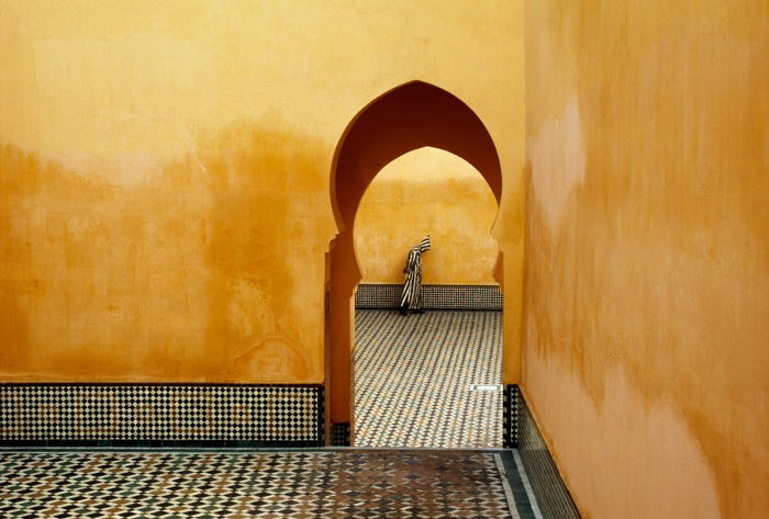 Man seen through Arabic arch with yellow walls