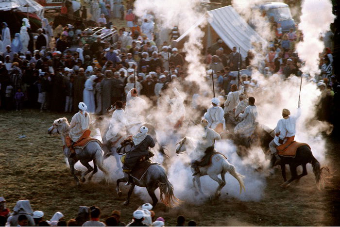 Pack of horsemen raising cloud of dust