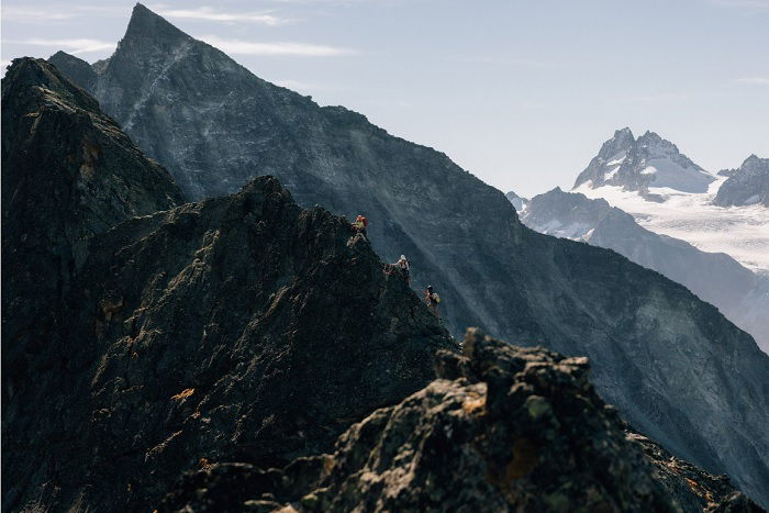 People scaling rocky mountain ridge