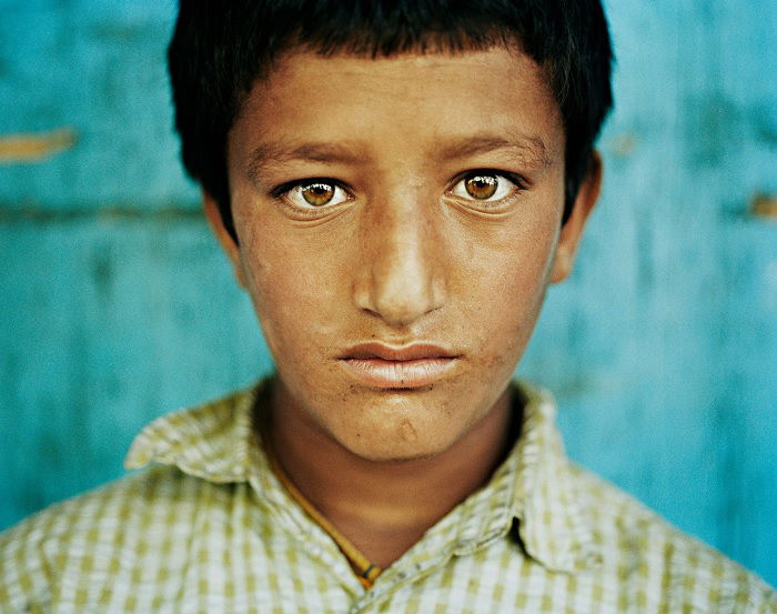 Close portrait of young Kashmir boy against blue wall