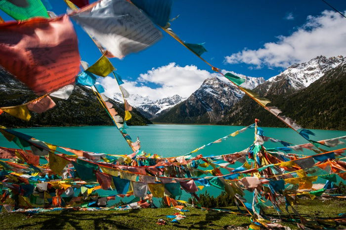 Prayer flags by a lake with mountains in the background