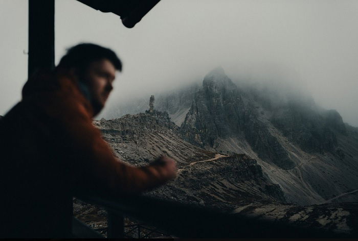 Man leaning on ledge in front of mountains