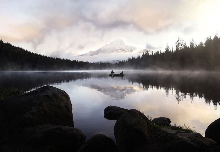 Two people on distant canoe on misty lake