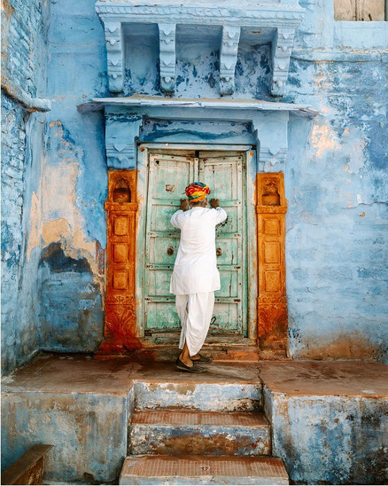 Man in white closing doors of colorful building