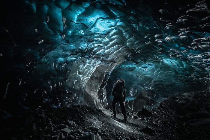 Man inside dark ice cave