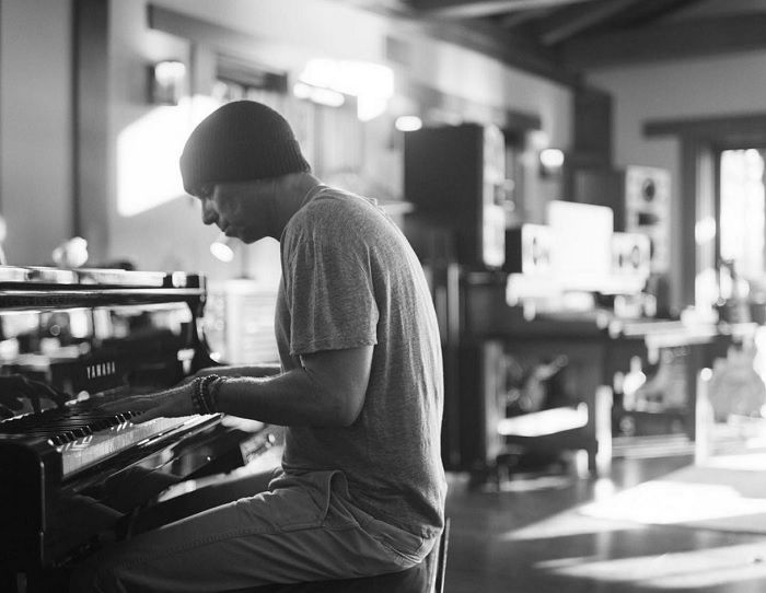 Man in beanie hat sitting at a piano