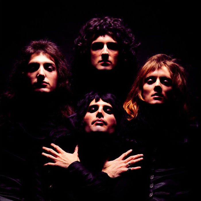 All four members of Queen against black backdrop