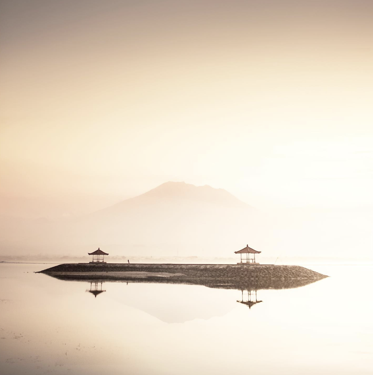 photo of pagodas in a lake with mountain in background