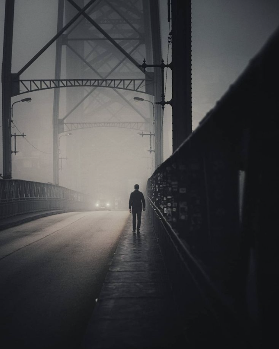 man on misty bridge at night