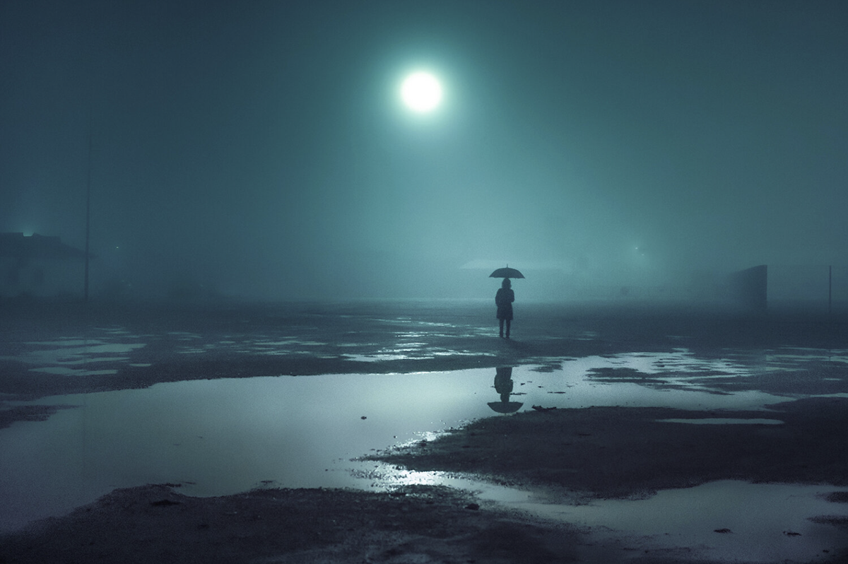 photo of person standing by river in moonlight